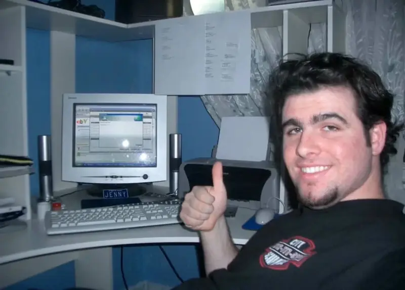 A young Christopher Maddaloni at a home computer desk, smiling and giving a thumbs up beside an old tube monitor