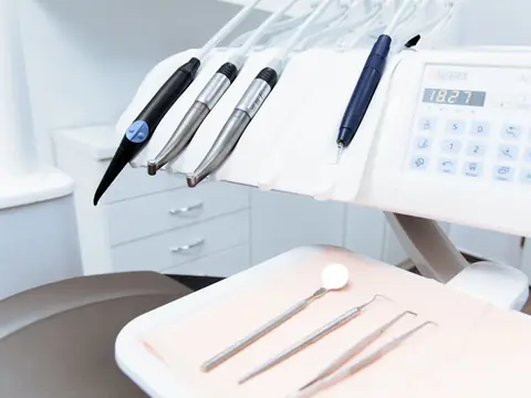 Dental instruments laid on a tray under a rack of handpieces and a control panel