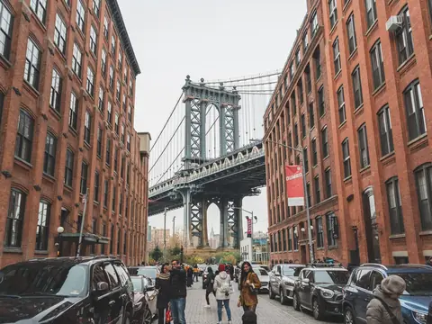 The Manhattan Bridge seen between brick warehouse buildings on a cobbled street in DUMBO, Brooklyn