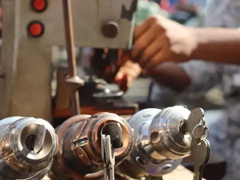 Hands working a key cutting machine, with keys in the clamps in front