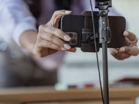 Two hands fixing a phone into the holder of a tripod