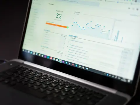 A laptop screen showing a dashboard with a large score of 32 and line charts