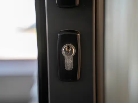 A lock cylinder in the edge of a dark door, close up