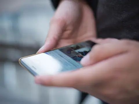 A thumb scrolling on a phone held in both hands