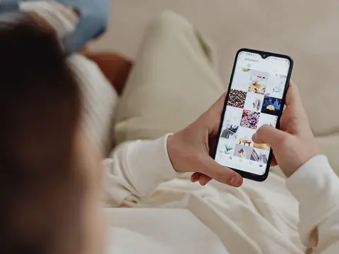 Two hands holding a phone that shows a grid of small photographs