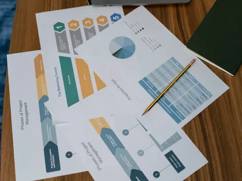 Printed report pages with charts and diagrams fanned out on a wooden desk with a pencil