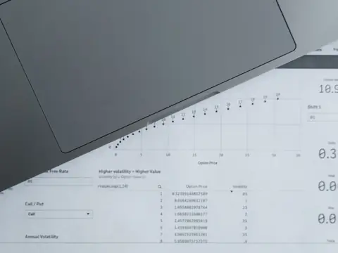 A printed table of figures lying beside a grey laptop