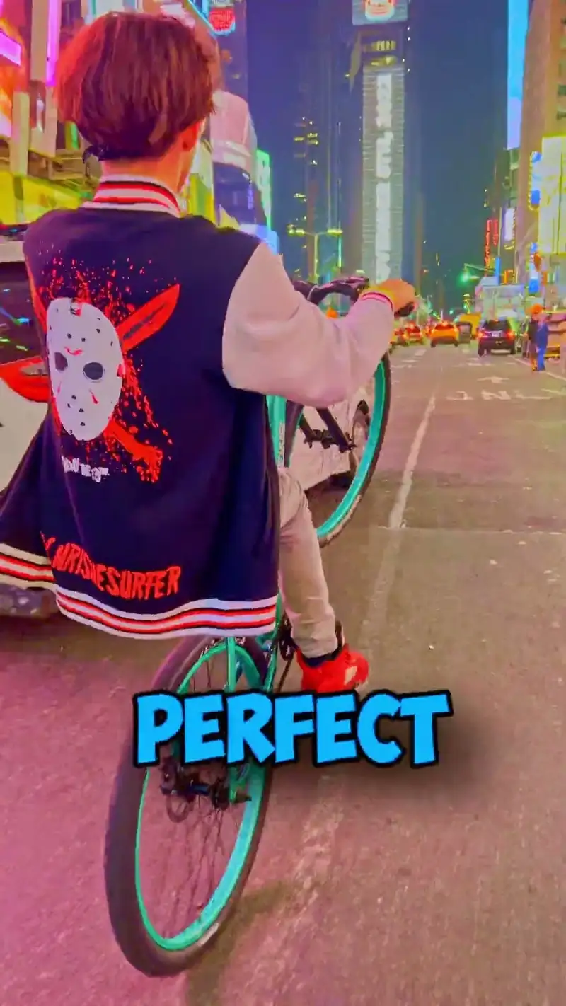 A frame from a ChrisTheSurfer Short: a rider in a ChrisTheSurfer jacket, seen from behind, on a wheelie through Times Square at dusk, with the caption PERFECT