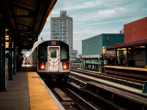 A number 6 subway train arriving at an elevated station platform in the Bronx