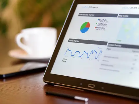 A tablet on a wooden table showing a traffic overview with a pie chart and a line chart