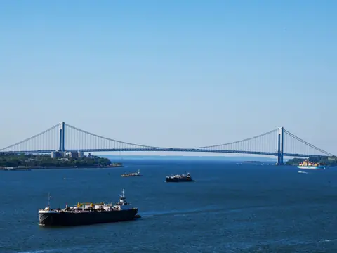 The Verrazzano-Narrows Bridge across blue water with ships passing, on a clear day